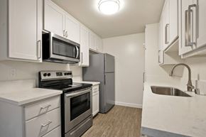 Los Angeles apartment for rent - A kitchen with white cabinets and a black microwave.