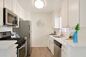 Valley Village apartment for rent - A kitchen with white cabinets and a black stove top oven.