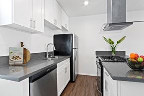 Los Angeles apartment for rent - A kitchen with white cabinets and black countertops.