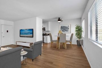 Studio City apartment for rent - A living room with a grey couch, a dining table with chairs, a ceiling fan, and a painting on the wall.