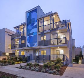 Los Angeles apartment for rent - Modern multistory building with illuminated balconies at dusk at Cypress Co-Living Apartments, Los Angeles, CA 90024