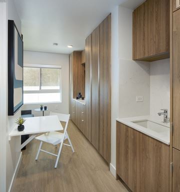 Los Angeles apartment for rent - A modern kitchen with wooden cabinets and a white table.