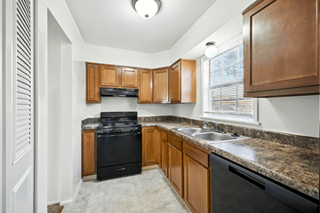 Indianapolis apartment for rent - A kitchen with wooden cabinets and a black stove top oven.