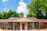 Vincennes apartment for rent - A small building with a red door and windows surrounded by greenery.
