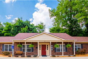 Vincennes apartment for rent - A small building with a red door and windows surrounded by greenery.
