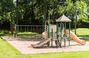 Indianapolis apartment for rent - Playground with slides and swings surrounded by trees at Carriage House West Apartments, Indianapolis, 46224