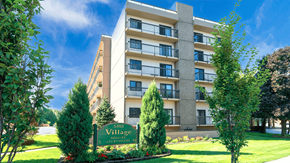 Williamsville apartment for rent - Exterior view of Village Square Apartments showcasing the building's design and landscape.