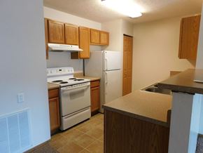 West Lafayette apartment for rent - Kitchen with white appliances and wooden cabinets at Chapelgate Park Apartments