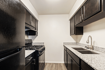 Kendallville apartment for rent - A black fridge and stove in a kitchen with black cabinets.