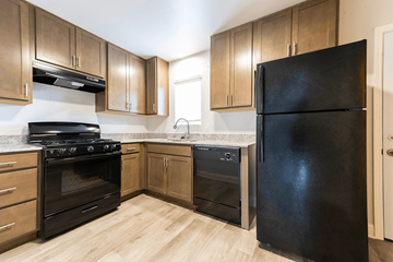 Indianapolis apartment for rent - A black refrigerator stands in a kitchen with wooden cabinets and a black stove.