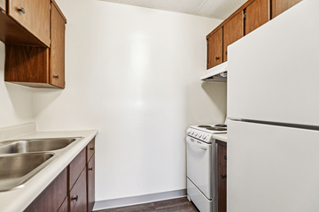 Lafayette apartment for rent - A kitchen with a white refrigerator, a stainless steel sink, and wooden cabinets.