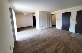 Indianapolis apartment for rent - Spacious living room with dark wood door and carpet at Carriage House West Apartments, Indiana, 46224