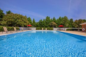 Suffolk apartment for rent - Apartment community amenity swimming pool with chairs and umbrellas at  King's Landing Apartments.