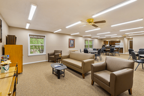 Bloomington apartment for rent - A spacious waiting room with a piano, chairs, and a ceiling fan.