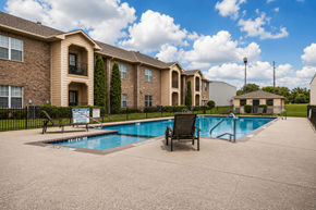 Sulphur Springs apartment for rent - A pool area in front of a brick apartment building.