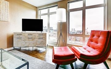 Seattle apartment for rent - a living room with two red chairs and a television on a dresser