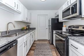 Clinton Township apartment for rent - a kitchen with white cabinets and black appliances