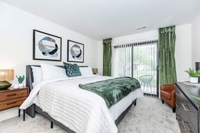 Clinton Township apartment for rent - a bedroom with a bed and a sliding glass door to a balcony
