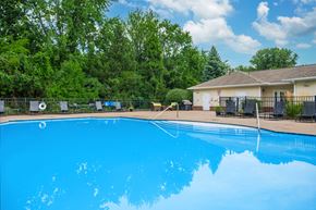 Sheffield Lake apartment for rent - A large blue swimming pool surrounded by trees and a house.