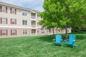Avon apartment for rent - two blue chairs sitting under a tree in front of an apartment building
