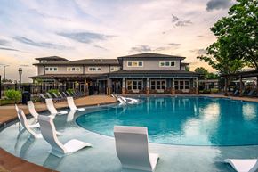 Blacksburg apartment for rent - a swimming pool with chairs and a building in the background
