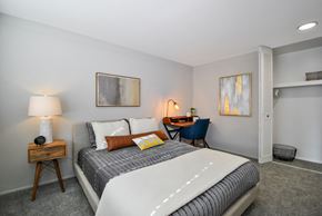 Harper Woods apartment for rent - A bedroom with a large bed and a desk with a chair.