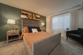 Southfield apartment for rent - A bedroom with a large bed and a nightstand with a lamp.