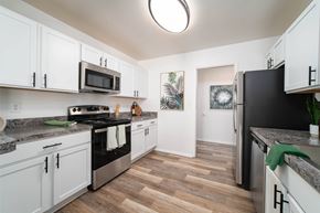 Southfield apartment for rent - A kitchen with white cabinets and a black fridge.