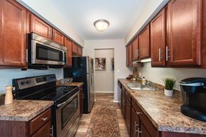 Troy apartment for rent - A kitchen with dark wood cabinets and granite countertops.