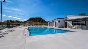 Mchenry apartment for rent - A large outdoor swimming pool with lounge chairs and a building in the background.