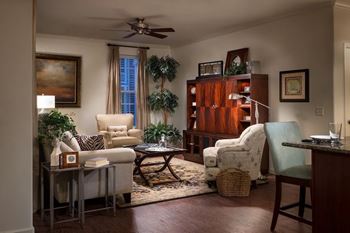 A living room with a white chair, a brown table, and a ceiling fan