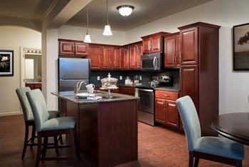 A kitchen with brown cabinets and a black refrigerator