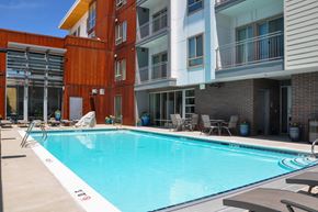 Salt Lake City apartment for rent - A swimming pool in front of a building with a red and white striped wall.
