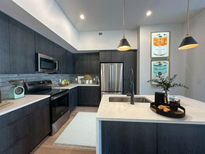 Salt Lake City apartment for rent - Liberty Duet Apartments, Salt Lake City, Utah; A modern kitchen with dark wood cabinets and a white countertop, kitchen island, stainless steel appliances..