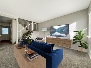 Draper townhouse for rent - A living room with a blue couch, a wooden coffee table, a staircase, and a large painting on the wall.