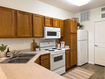 West Jordan townhouse for rent - A kitchen with wooden cabinets and white appliances.