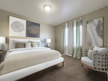 West Jordan townhouse for rent - A bedroom with a large bed and a chair.