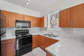 Homestead townhouse for rent - A kitchen with wooden cabinets and black appliances.