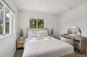 Homestead townhouse for rent - A bedroom with a large bed, a nightstand, and a mirror.