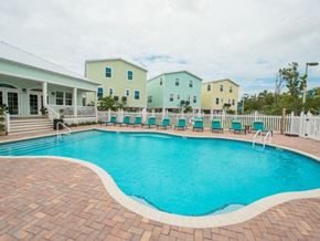 Marathon apartment for rent - A pool surrounded by a brick border with chairs around it.