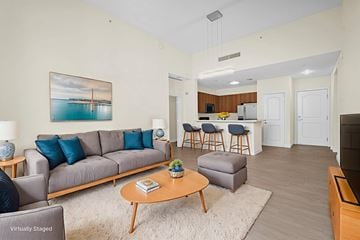 Miami townhouse for rent - A living room with a grey couch and a painting of a bridge over water.