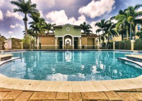 Homestead townhouse for rent - a large swimming pool in front of a house with palm trees