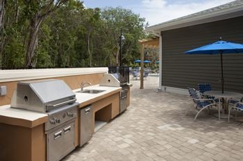 A patio with a grill and chairs.