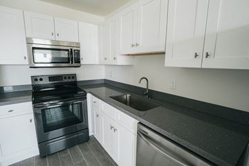 Marathon apartment for rent - a kitchen with white cabinets and black counter tops and stainless steel appliances