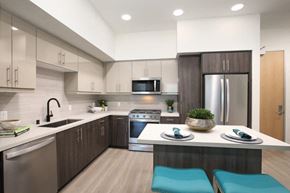 Laguna Niguel apartment for rent - A modern kitchen with a stainless steel refrigerator, a microwave, and a dining table set for two.