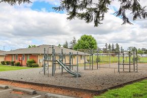 Lakewood apartment for rent - A playground with a slide and swings in front of a building.