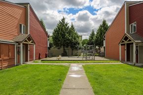 Tacoma apartment for rent - A playground with a slide and a green lawn in front of a red building.