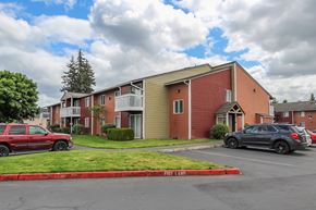 Tacoma apartment for rent - A red car is parked in front of a red brick building.