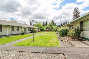 Tacoma apartment for rent - A grassy area in front of a building with a lamp post.
