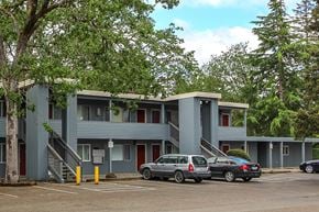Lakewood apartment for rent - A grey building with a red door and a tree in front.